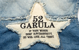 Macro view of light blue denim vest with white star canvas patches and frayed edge details