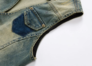 Detail of vintage washed denim vest showing retro metal buttons and patchwork pocket