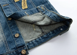 Dettaglio del gilet in denim blu con bottoni vintage e toppa con lettera ricamata gialla