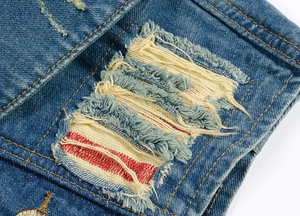 Detailed macro view of distressed denim vest featuring red and white frayed fabric lining