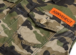 Macro detail of camouflage denim vest with orange embroidered patch and metal button