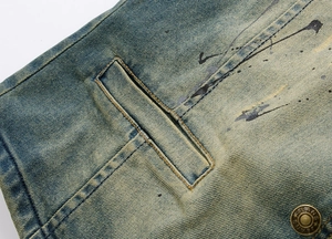Detail of vintage washed denim vest featuring ink splatters and star embossed metal button