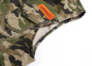 Close-up of camouflage denim vest with embossed metal eagle button and orange label
