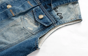Detailed close-up of blue washed denim vest featuring vintage buttons and embroidery