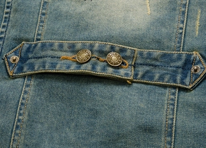 Detail of blue denim vest featuring metal adjustment buckle and orange contrast stitching
