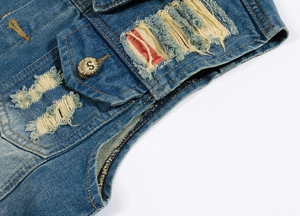 Detailed macro view of distressed denim fabric with ripped holes and branded metal buttons