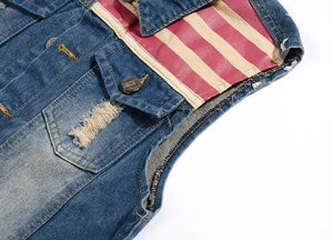 Détail du gilet en jean bleu avec patchs rayés rouge et blanc et poches vieillies