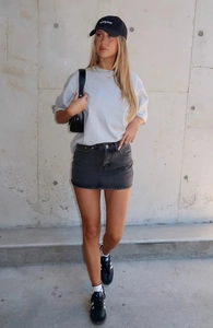 Outdoor-Streetstyle-Ansicht eines eng anliegenden schwarzen Jeansminirocks mit grauem T-Shirt