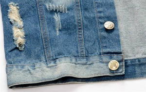 Macro shot of blue distressed denim vest with metal buttons and classic orange stitching