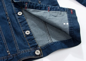 Detail of dark blue denim jacket featuring metal buttons, rivets and contrast stitching