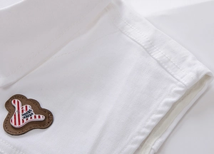 Dettaglio ravvicinato delle cuciture e della toppa in pelle su un gilet di jeans bianco