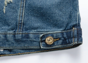 Dettaglio dell'orlo in denim blu con doppia cucitura gialla e bottone in metallo inciso