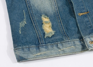 Detailed macro shot of distressed denim vest with ripped holes and contrast yellow stitching