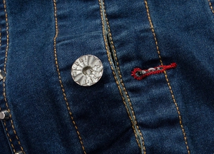 Macro shot of dark blue denim jacket with contrast stitching and branded silver button