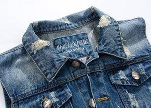 Detail of distressed denim vest with frayed holes and vintage metal button closure