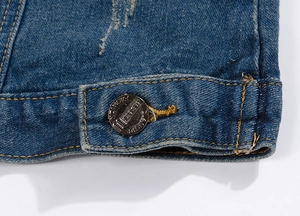 Détail du tissu en denim délavé avec coutures jaunes et boutons métalliques de jeans