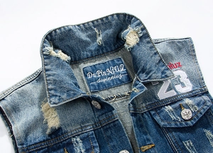 Detail of distressed denim vest featuring a number 23 patch and vintage metal buttons