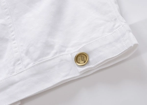 Dettaglio ravvicinato del tessuto denim bianco con bottone in bronzo a piuma
