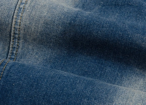 Gros plan du tissu denim délavé bleu avec coutures détaillées à double aiguille