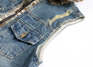 Detail of distressed blue denim vest showing ripped texture, metal button, and camo lining