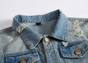 Detail of light blue washed denim jacket featuring vintage distressing and gold buttons