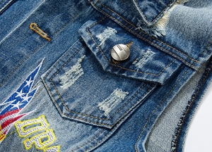 Close-up of distressed blue denim vest featuring star embroidery and embossed metal buttons