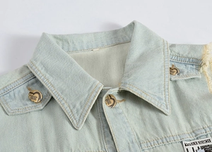 Close-up of light blue denim vest showing heart-shaped metal buttons and stylish woven label