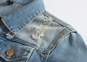 Detail view of denim jacket showing retro gold anchor button and distressed textures