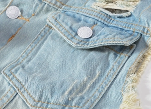 Detailed macro of distressed light blue denim vest with metal buttons and frayed texture