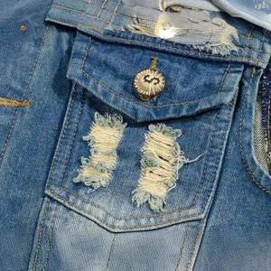 Close-up of light blue distressed denim vest with chest pocket and metal button