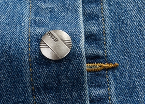 Macro shot of silver metal button with JEANS engraving on blue denim fabric texture