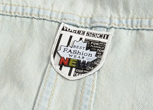 Close-up of denim vest showing shield-shaped patch with stripe pattern and embroidery