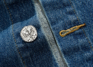 Macro shot of denim vest with metallic buttons featuring embossed double eagle crown