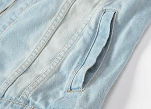 Detail of light blue denim vest showing side pocket design and neat stitching quality