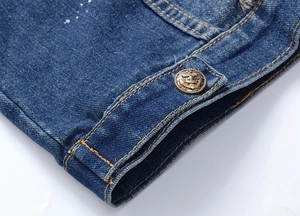Close-up of blue denim jacket showing white paint splatter and anchor-motif bronze button