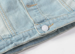 Close-up of light blue denim vest hem with silver metal buttons and jeans wear engraving