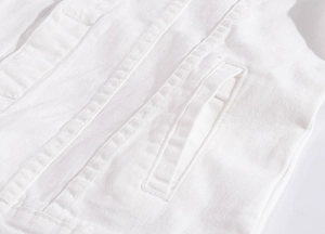 Macro shot showing detail of double-stitched seams and twill texture on white denim jacket