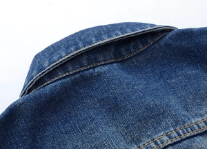 Detailed macro view of denim jacket collar showing orange contrast stitching and washed fabric