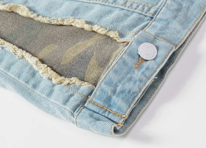 Detail of light blue denim vest with distressed holes and camouflage fabric lining