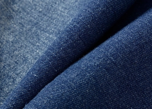 Close-up of deep blue twill denim fabric texture with fine weave details and natural luster