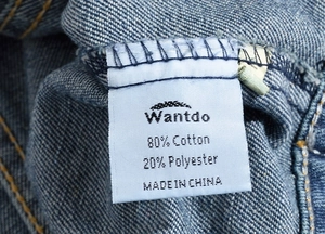 Detail of the washing label showing 80% cotton and 20% polyester on a denim vest