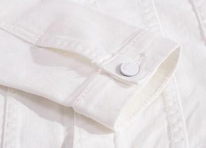 Close-up of white denim jacket cuff featuring a metal button with jeans engraving