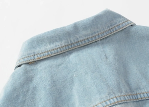 Close-up of lapel collar and stitching details on a light blue denim vest for men