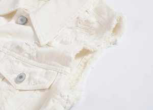 Detailed close-up of distressed denim vest featuring fringed edges and metal buttons