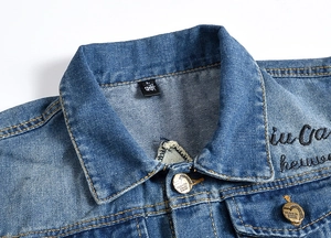 Detail of blue denim vest collar with brand tag and metal buttons with fashion lettering