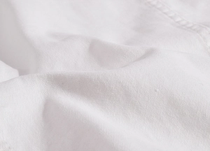 Macro shot of white twill denim fabric texture with high-density diagonal weave patterns