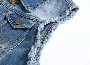Detailed macro view of distressed light blue denim vest showing raw fringe armholes