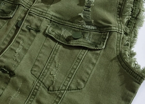 Detailed close-up of military green denim vest showing frayed edges and distressed texture
