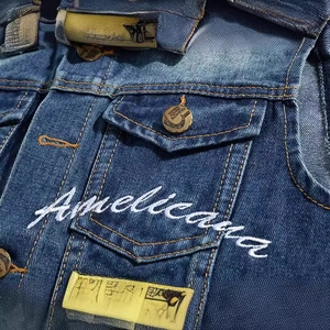 Close-up of slim-fit dark blue denim vest with Americana embroidery and metal buttons
