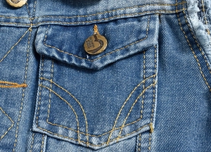 Detailed close-up of blue denim vest featuring orange contrast stitching and metal button